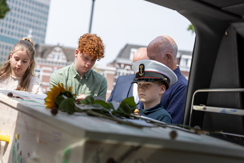 GonnieBax4 Handen die de handen van een overledene in de kist voor het sluiten vasthouden.