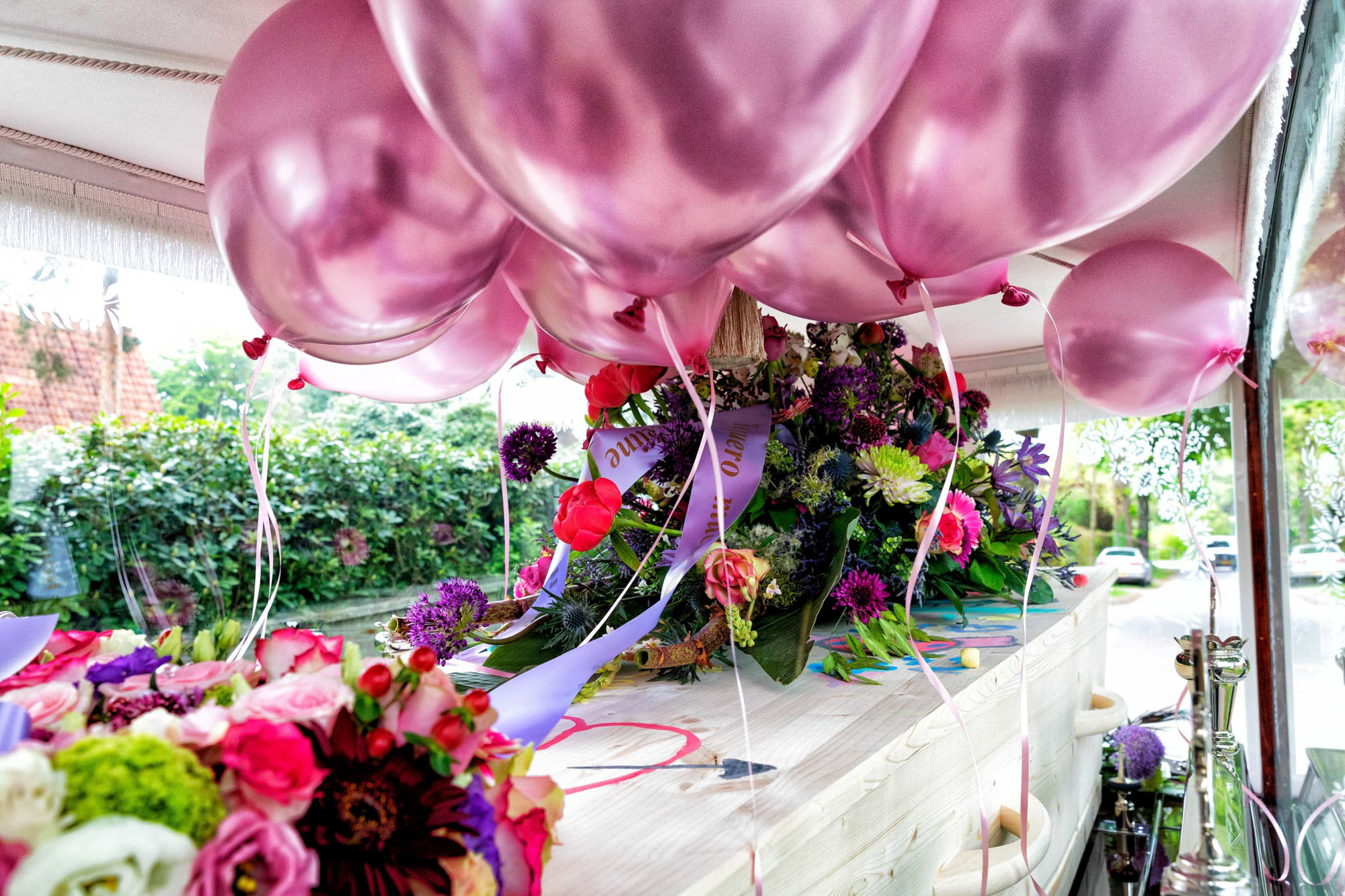 Laatste groet van twee mensen bij de kist voor het sluiten omringd door gekleurde bloemen bij het raam