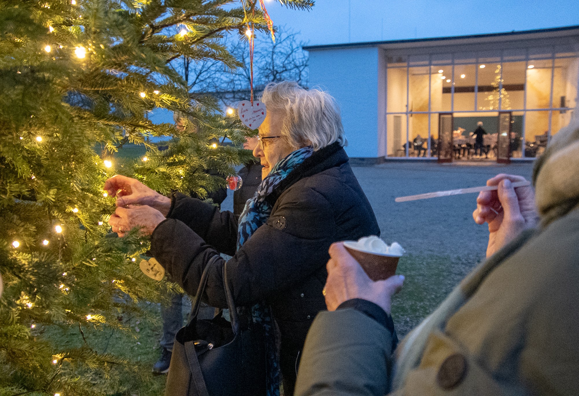 oude vrouw hangt een ornament in de kerstboom buiten